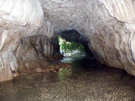 ΘΕΟΤΙΚΟ - ΕΝΑ ΘΑΥΜΑ ΤΗΣ ΦΥΣΗΣ ΣΜΙΛΕΜΕΝΟ ΑΠΟ ΘΕΪΚΟ ΧΕΡΙ Το ποτάμιο σπήλαιο "Θεοτικό" στον ποταμό Φιδάκια κοντά στον Δρυμώνα. Ένα σπάνιο θαύμα της φύσης σμιλεμένο από "θεϊκό" χέρι, όπου το ποτάμι διέρχεται για πολλές δεκάδες μέτρα μέσα από το υπέροχο αυτό σπήλαιο με το πολύχρωμο ανάγλυφο στα τοιχώματα και στην οροφή, σε τμήματα του οποίου μάλιστα σχηματίζονται μικροί αλλά υπέροχοι σταλακτίτες, ενώ στα ίδια σημεία αναβλύζουν και διάσπαρτες μικροπηγές. Άλλοι θεωρούν το σπήλαιο φυσικό γεφύρι και δεν έχουν και άδικο, αφού το έξω πάνω μέρος του σπηλαίου γεφυρώνει με φυσικό τρόπο τις πλαγιές εκατέρωθεν του ποταμού. Το σπήλαιο προσεγγίζεται μέσω μονοπατιού που ξεκινάει κοντά από τον Δρυμώνα σε απόσταση περί τα 17 χμ. από Θέρμο (15 χμ. σε ασφάλτινη διαδρομή και 2 σε χωμάτινη). (Φωτογραφία: Σμάνης Πέτρος - Περιγραφή: Κωστακόπουλος Νίκος)